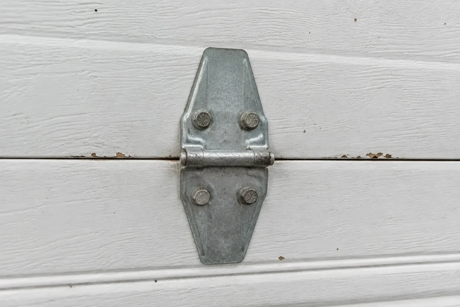 Metal center hinge across a seam in a white sectional garage door. — Garage Door Hinge Replacement, Kitchener